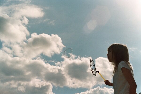 A little girl inflates soap bubbles