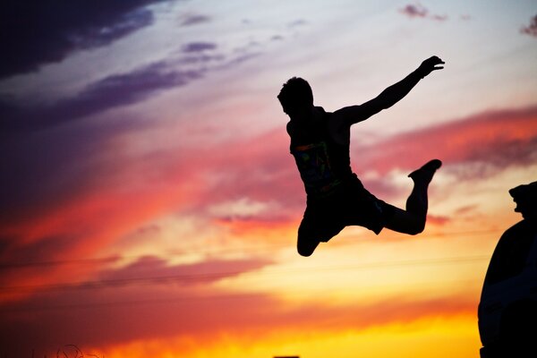 Silhouette of a guy jumping against the sunset background