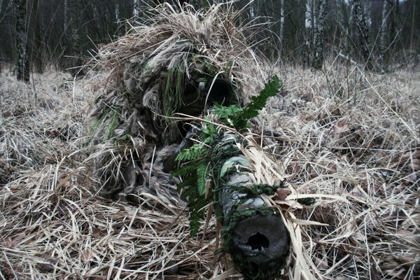 Sniper with a rifle in camouflage disguised