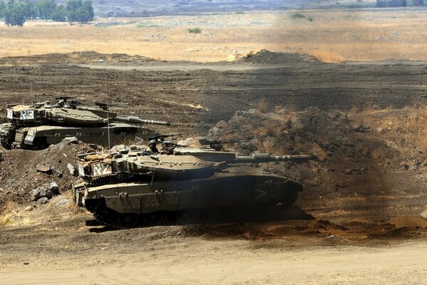 Military tanks roll through the desert