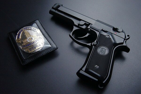 Gun and badge of a police officer on a black background