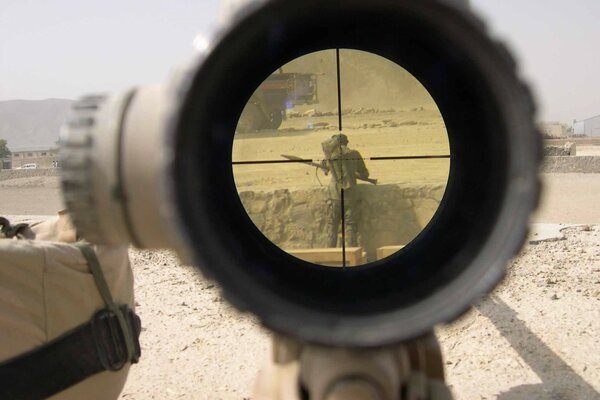 A military man in the desert in the sight of a machine gun