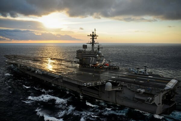 Aircraft carrier in the ocean at sunset