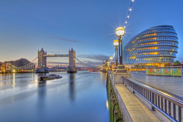 The embankment of evening London. Thames and Tower Bridge in the light of lanterns