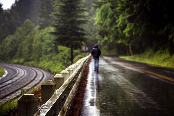 Un homme marche sur la route sous la pluie