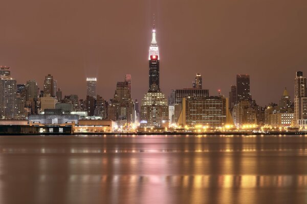 Illuminazione notturna dei grattacieli di New York vicino al fiume
