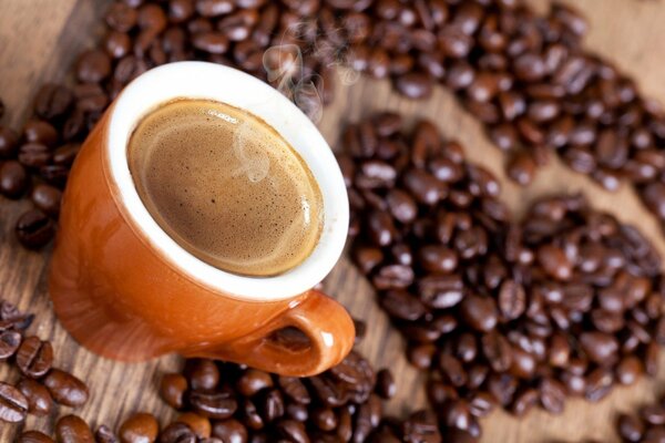 A cup of coffee with foam near the coffee beans