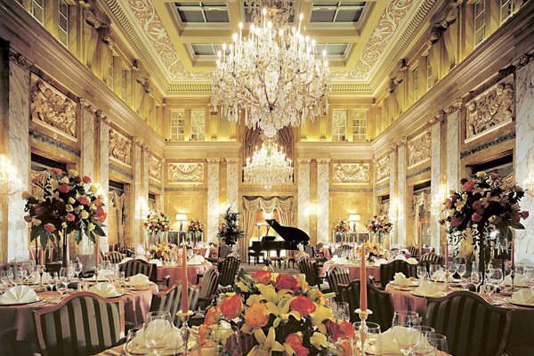 Salle avec tables ornées de bouquets, lustres en cristal et piano noir