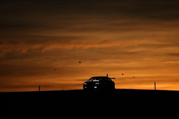 Silhouette of a car against a sunset background