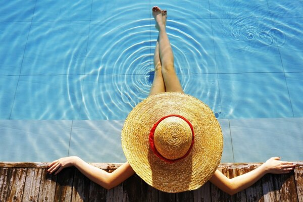 She sat down in the pool with a hat on her head