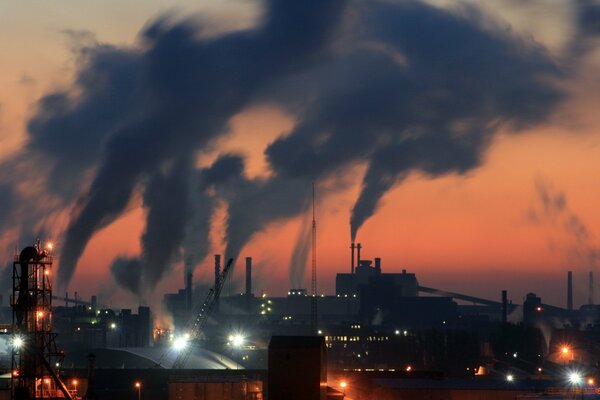 Fumo di tubi di fabbrica contro il cielo notturno