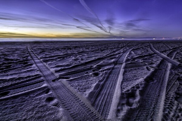 Tire tread marks on the sand with a beautiful sky