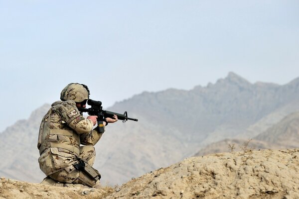 Photo of a soldier with a gun in the mountains