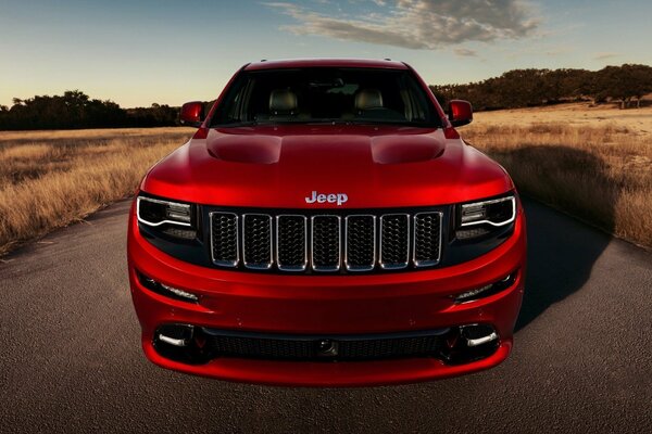 Roter Jeep Grand Cherokee auf Feldhintergrund