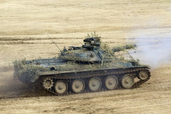 El tanque militar disfrazado paja en el campo