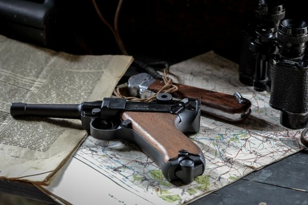 A pistol binoculars and a newspaper lying on the table