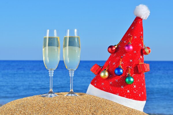 Sombrero de Navidad con copas de champán en la arena