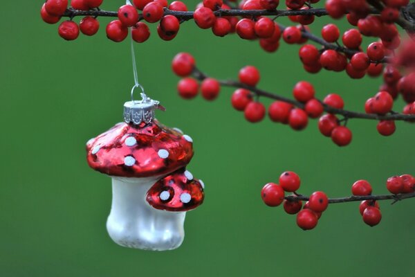 On the branches are berries and a Christmas toy on a green background