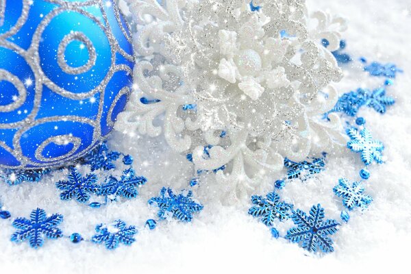 Świąteczna kula na śniegu z niebieskimi płatkami śniegu
