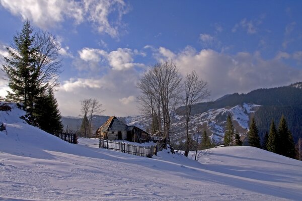Зимний пейзаж со снежными горами и одиноким домиком
