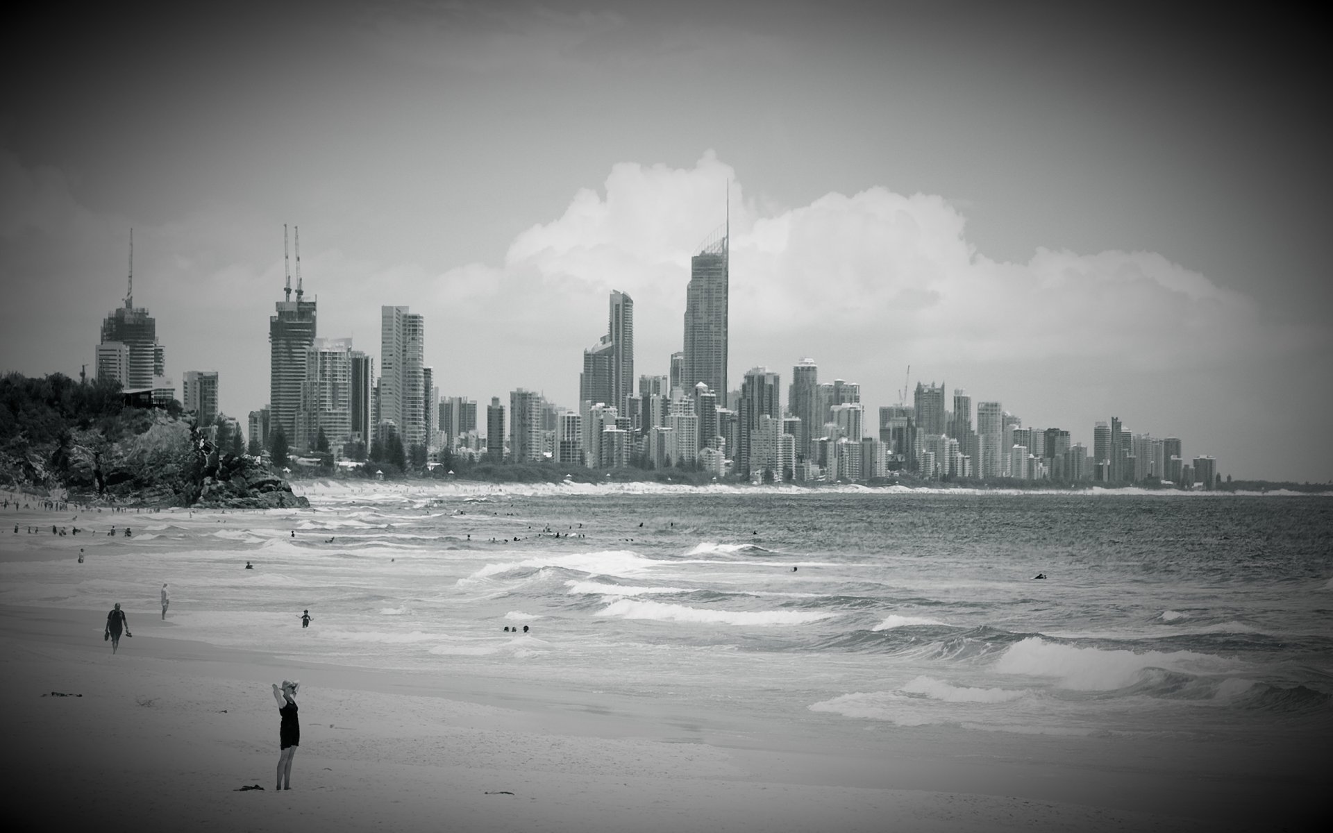 miasto plaża budynki wieżowce niebo chmury woda fale oceanu ludzie kąpią się raj dla surferów