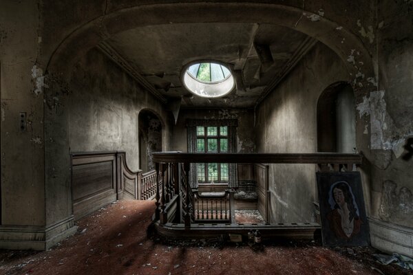 Round window above an old staircase in an abandoned mansion