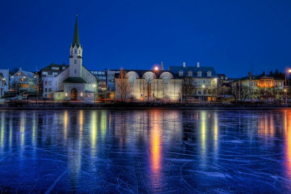 Views of Reykjavik at night over a pond bound by winter ice