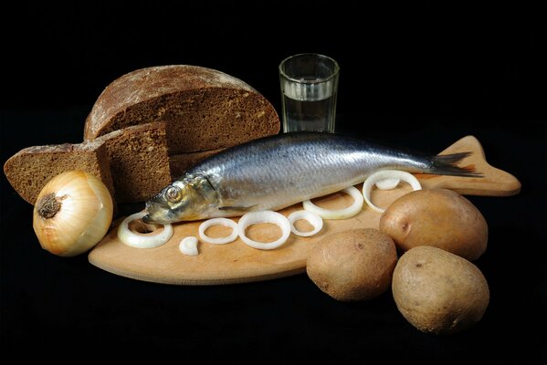 Naturaleza muerta arenque con cebolla, patatas y pan