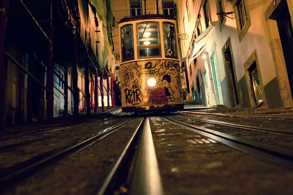 Tramway de nuit sur rails dans une rue étroite