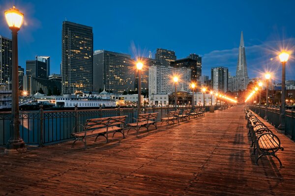 Passerelle et bancs sur fond de lumières de la ville