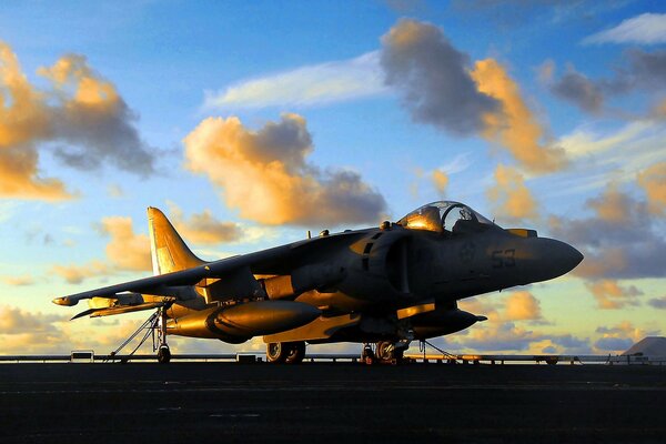 A tactical aircraft stands against the background of a cloudy sunset