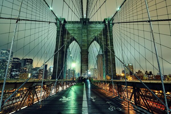 Il ponte di Brooklyn di New York, girato di notte contro i grattacieli che bruciano le luci