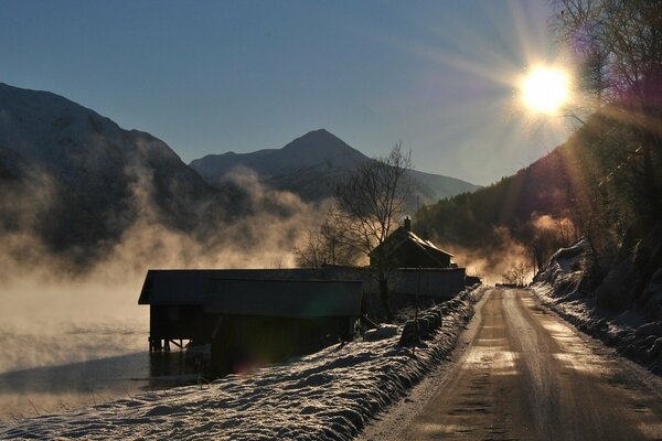 The gentle sun illuminating the winter road that runs next to the lake