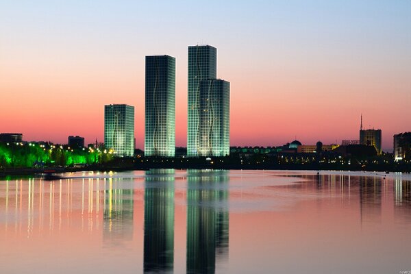 Die Wolkenkratzer von Astana spiegeln sich bei Sonnenuntergang im Wasser wider