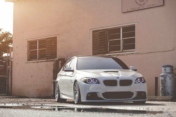 White BMW in daylight near a puddle