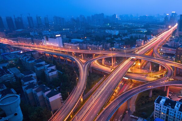 Paso elevado urbano iluminado al anochecer a vista de pájaro