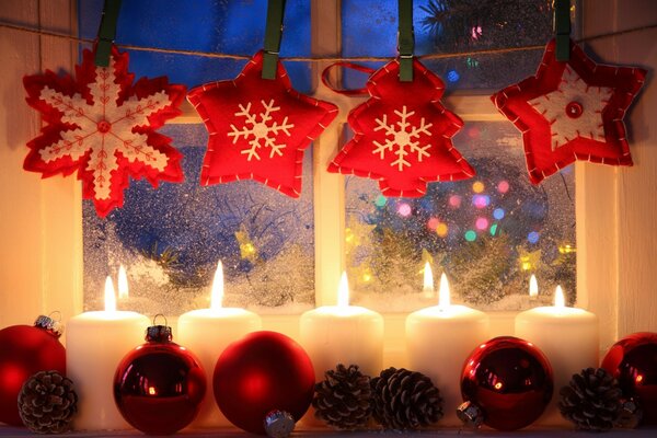 Christmas decorations. Candles and toys on a snow-covered window