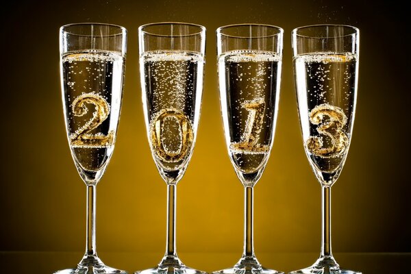 Quattro bicchieri di champagne con numeri che simboleggiano il prossimo anno