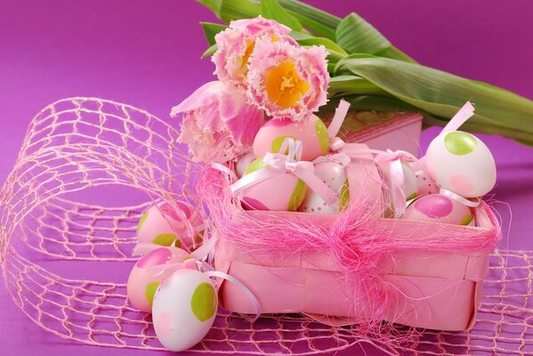 Uova di Pasqua in una scatola e tre tulipani in rosa