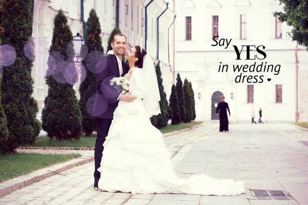 A couple of newlyweds on the background of a light building