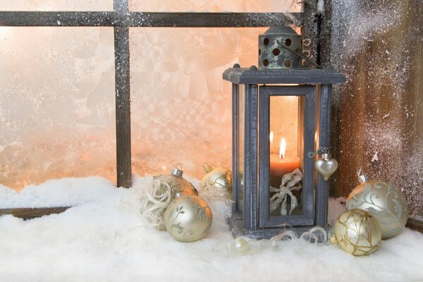 Lantern with candles on a snow-covered window