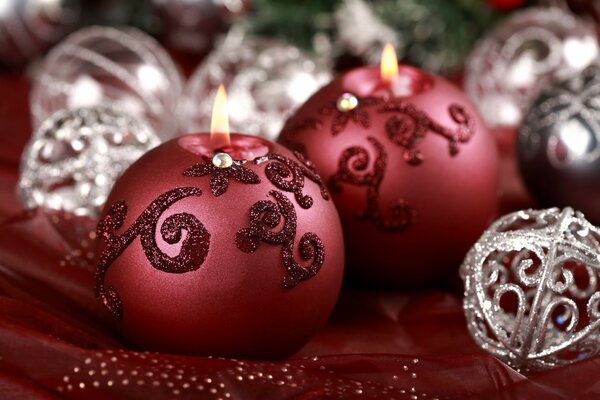 Velas de Navidad de color rojo oscuro entre bolas de plata