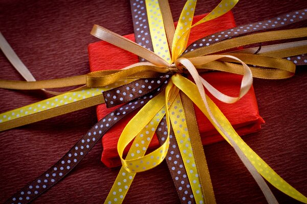 A gift decorated with colorful ribbons connected in a bow