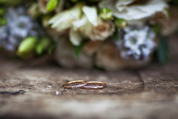 Primo piano di due anelli d oro sullo sfondo di un bouquet delicato