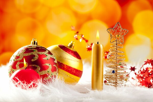 A pair of sequined balloons with a golden candle and a Christmas tree standing next to it