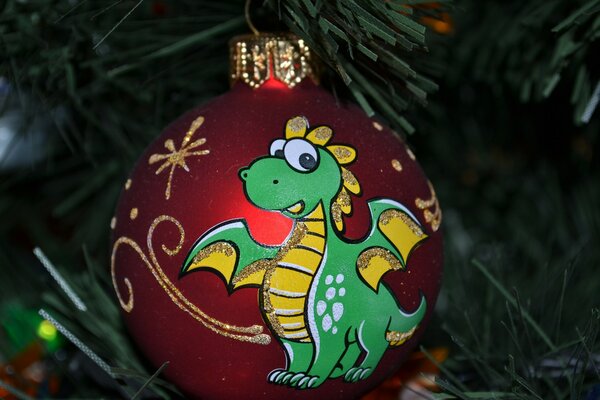 New Year s red balloon with a painted green dragon on the background of artificial green branches of the Christmas Tree