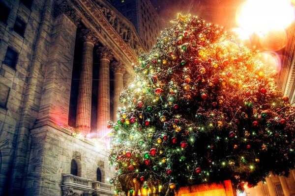 Abeto brillante decorado con juguetes de Navidad en el edificio