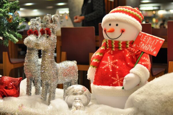 Snowman with reindeer near the Christmas tree