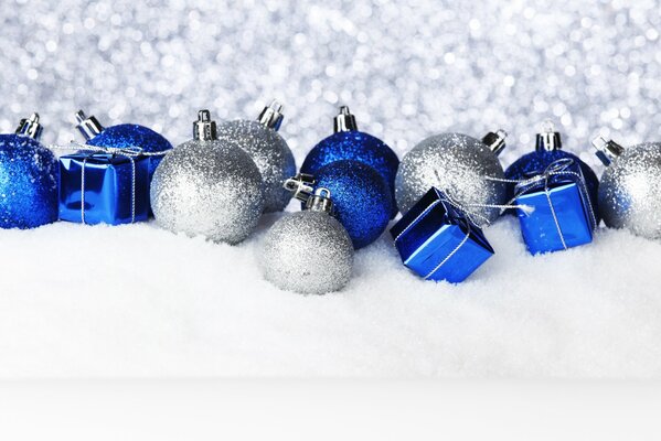 Los juguetes de Navidad azul plateado se encuentran en la nieve sobre un fondo brillante plateado