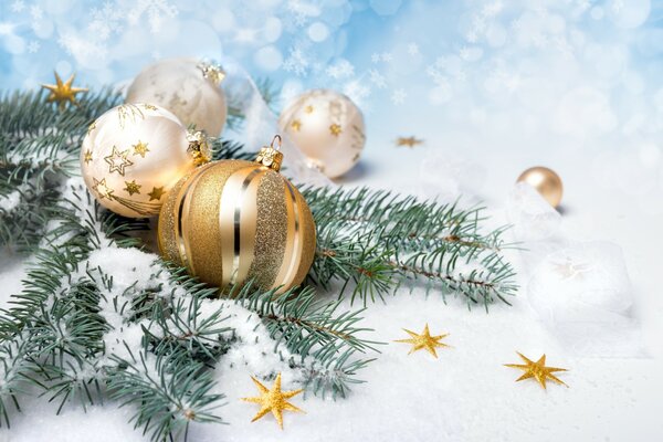 Golden balls on a branch of a fir tree against the background of snow